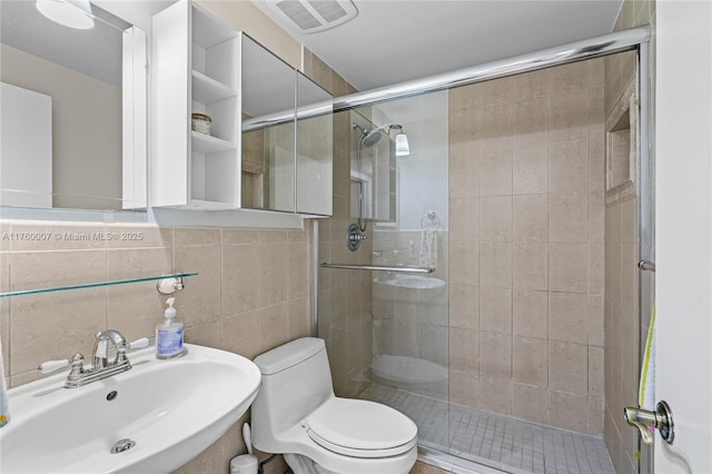 full bath featuring visible vents, toilet, a sink, tile walls, and a shower stall