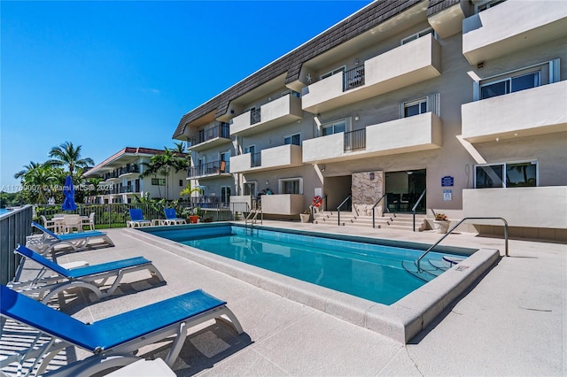 community pool with a patio and fence