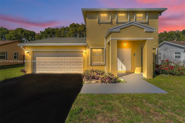 traditional-style home featuring a front yard, an attached garage, driveway, and stucco siding