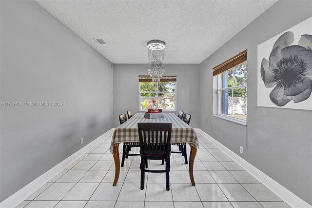 dining area featuring light tile patterned floors, visible vents, baseboards, and a notable chandelier