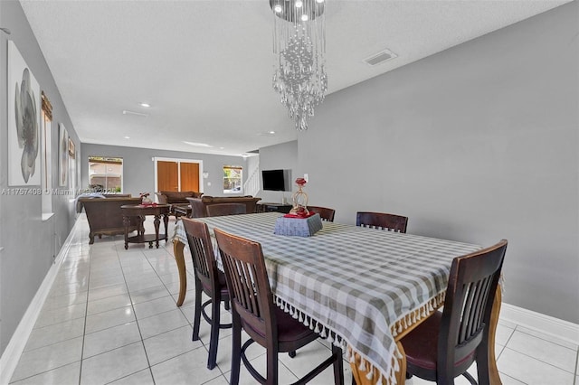 dining area with light tile patterned floors, visible vents, a chandelier, and baseboards