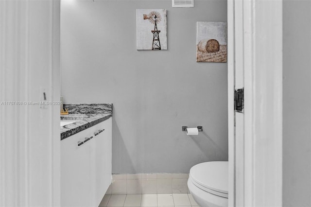 half bathroom featuring tile patterned floors, baseboards, toilet, and vanity