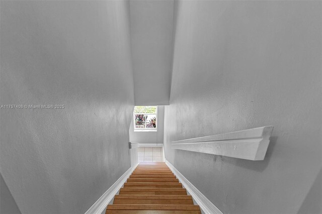 staircase featuring wood finished floors and baseboards