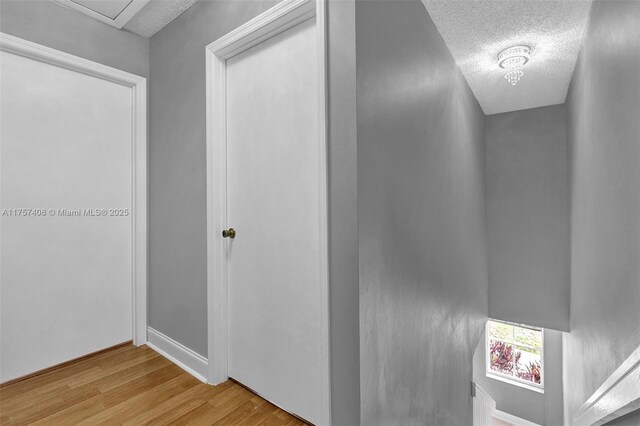 hall with wood finished floors and a textured ceiling