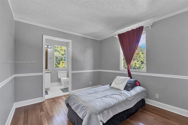 bedroom with ornamental molding, ensuite bathroom, a textured ceiling, hardwood / wood-style floors, and baseboards