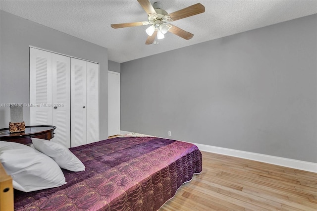 bedroom featuring wood finished floors, baseboards, and a textured ceiling