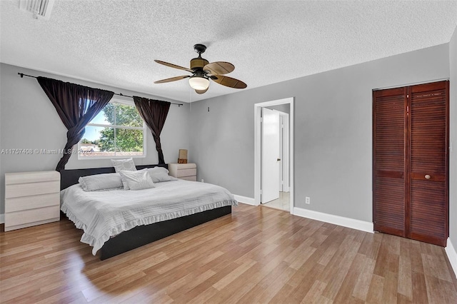 bedroom with visible vents, baseboards, a closet, a textured ceiling, and light wood-type flooring