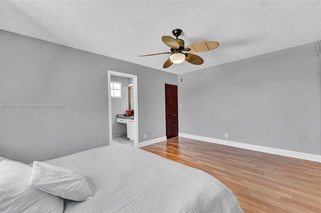 bedroom with a textured ceiling, a ceiling fan, baseboards, and wood finished floors