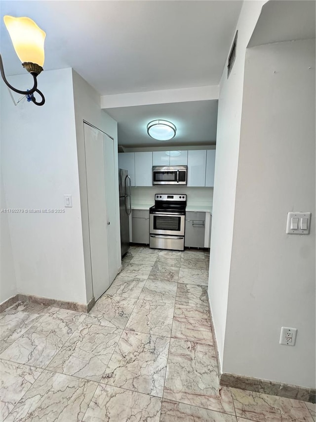 kitchen featuring light countertops, baseboards, marble finish floor, and appliances with stainless steel finishes