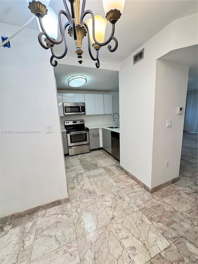 kitchen with marble finish floor, stainless steel appliances, light countertops, and a sink