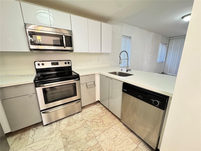 kitchen with light countertops, white cabinets, marble finish floor, stainless steel appliances, and a sink