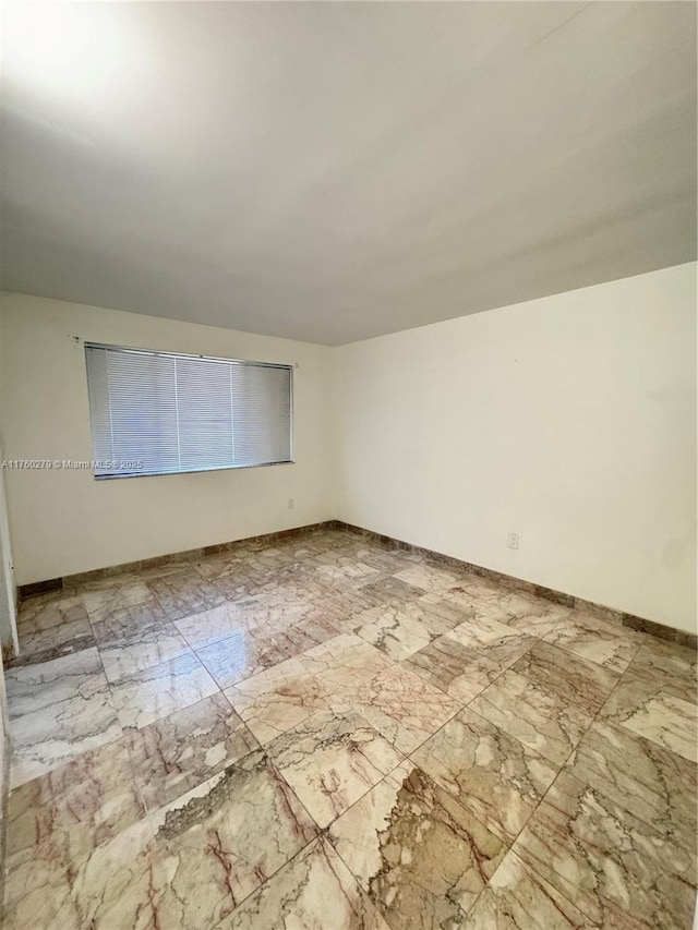 empty room featuring baseboards and marble finish floor