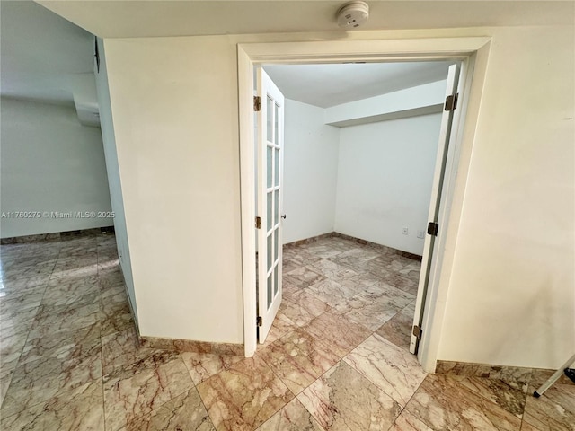 hall with marble finish floor and baseboards