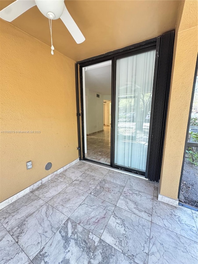 interior space with ceiling fan, marble finish floor, and baseboards