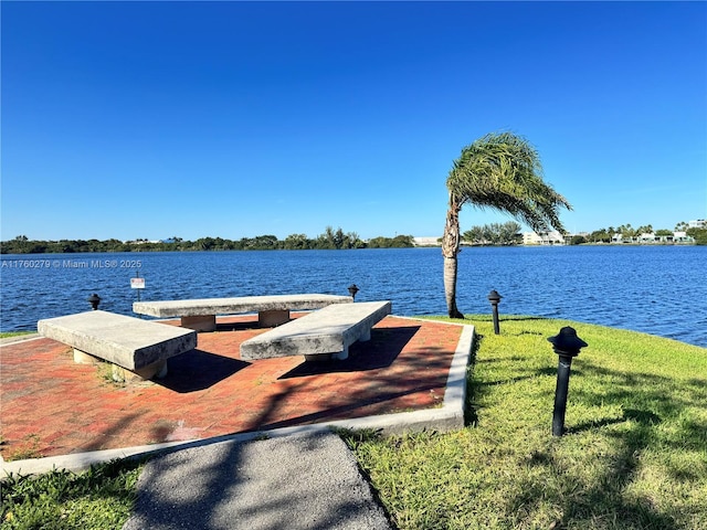 view of dock with a water view and a lawn