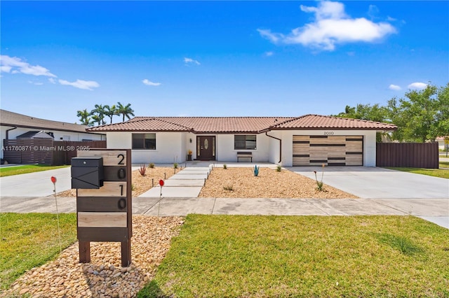 view of front of property featuring a front yard, fence, driveway, a garage, and a tile roof