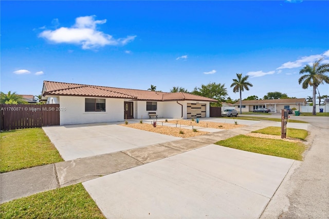 ranch-style home featuring driveway, a tile roof, fence, a front yard, and an attached garage