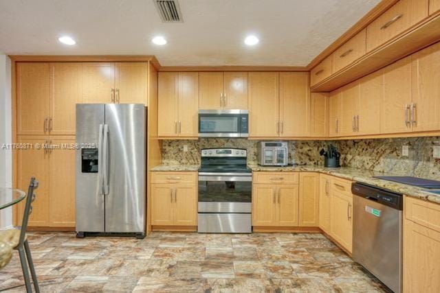 kitchen featuring light stone counters, light brown cabinets, visible vents, and appliances with stainless steel finishes