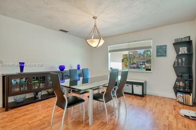 dining area featuring visible vents, baseboards, and wood finished floors