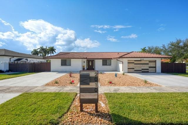 ranch-style home with a tile roof, fence, a garage, and driveway