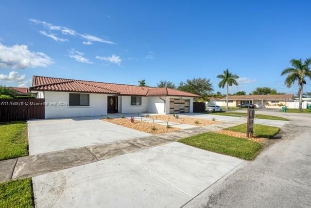 single story home featuring a tile roof, an attached garage, driveway, and stucco siding