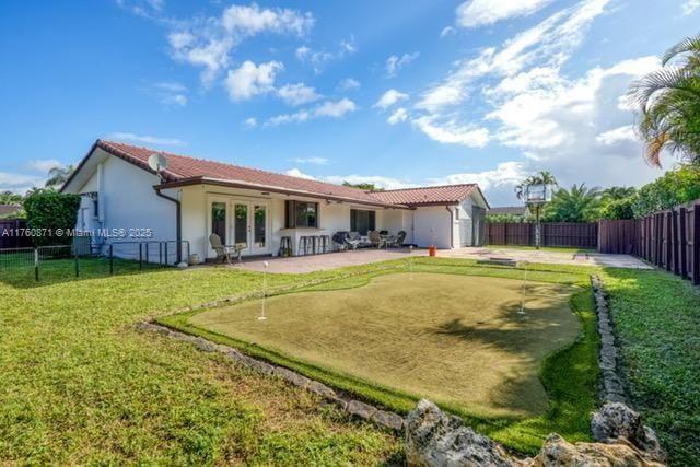 back of house featuring stucco siding, a fenced backyard, french doors, a yard, and a patio area