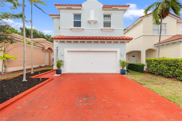 mediterranean / spanish home featuring a tile roof, stucco siding, driveway, and an attached garage