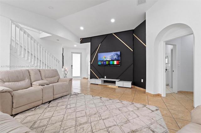 tiled living room featuring lofted ceiling, recessed lighting, arched walkways, baseboards, and stairs
