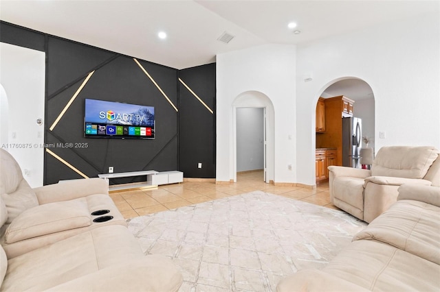 living room featuring vaulted ceiling, light tile patterned floors, visible vents, and arched walkways
