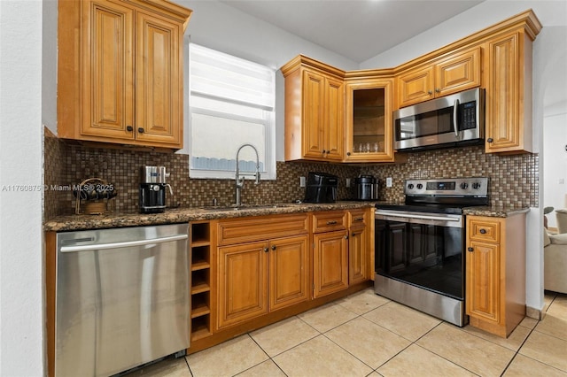 kitchen featuring backsplash, dark stone countertops, appliances with stainless steel finishes, and a sink