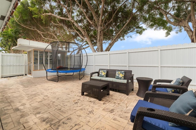 view of patio / terrace with an outdoor living space, a trampoline, and a fenced backyard