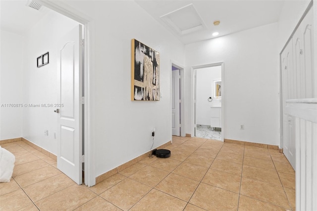 hall featuring attic access, light tile patterned floors, baseboards, and visible vents