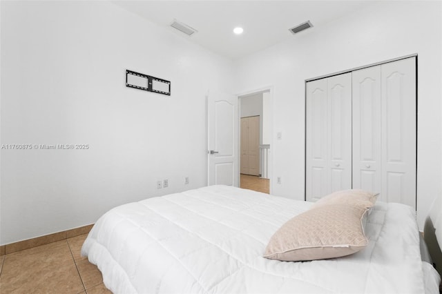 bedroom with light tile patterned flooring, baseboards, visible vents, and a closet