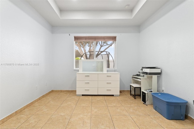 bedroom with a tray ceiling, light tile patterned floors, and baseboards