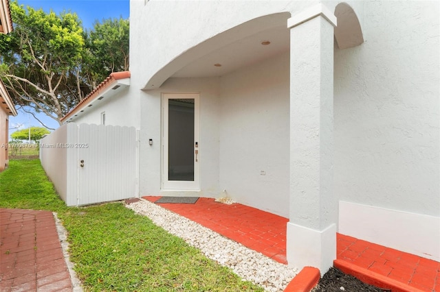 doorway to property with stucco siding and fence