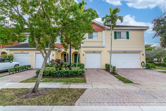 view of property with stucco siding, an attached garage, and decorative driveway