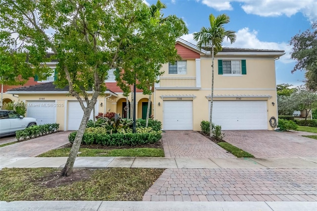 multi unit property featuring stucco siding, driveway, and a garage