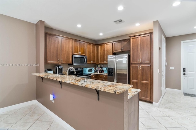 kitchen featuring a peninsula, light stone countertops, stainless steel appliances, and light tile patterned floors