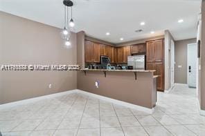 kitchen featuring stainless steel appliances, a peninsula, baseboards, a breakfast bar, and hanging light fixtures