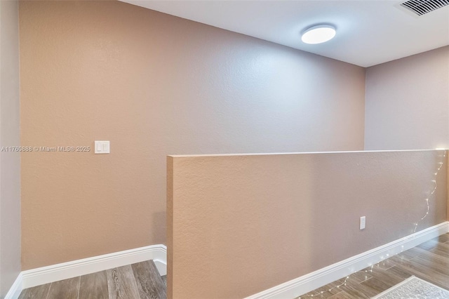 interior space featuring baseboards, wood finished floors, and visible vents