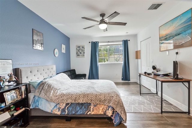 bedroom featuring wood finished floors, visible vents, baseboards, and ceiling fan