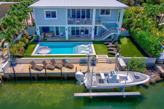 rear view of property with a patio, a yard, stairs, boat lift, and metal roof