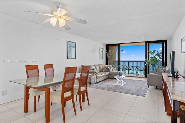 dining space with floor to ceiling windows, light tile patterned floors, and ceiling fan