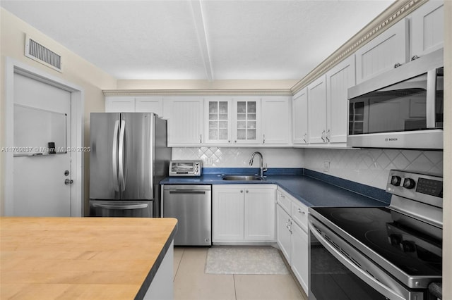 kitchen with visible vents, wooden counters, glass insert cabinets, appliances with stainless steel finishes, and a sink