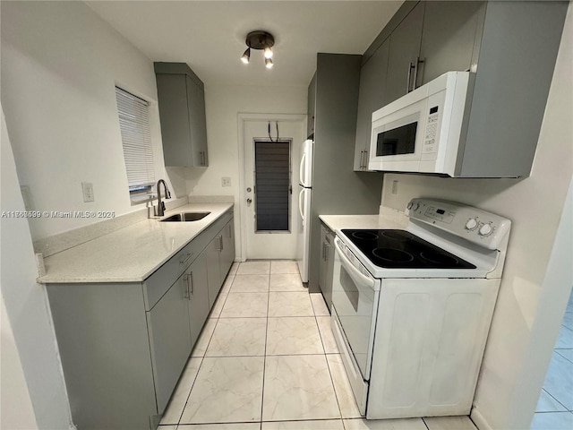 kitchen featuring a sink, white appliances, and gray cabinetry