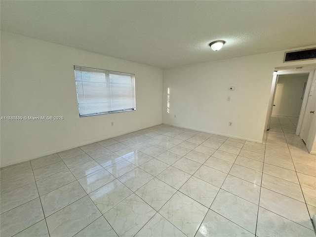 empty room featuring light tile patterned floors, visible vents, and a textured ceiling