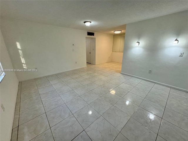 spare room featuring baseboards and a textured ceiling