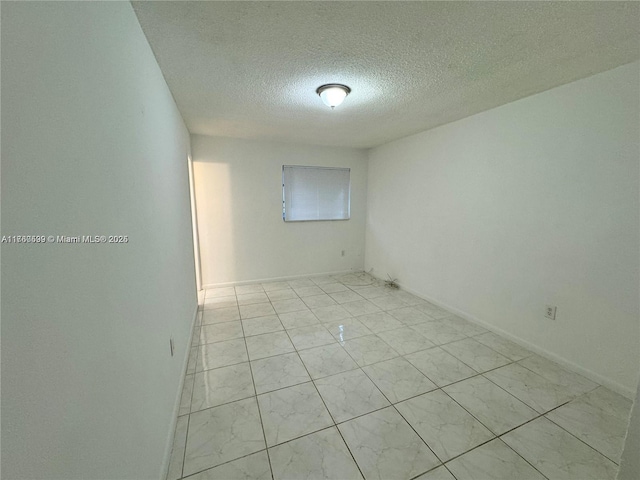 spare room with baseboards and a textured ceiling