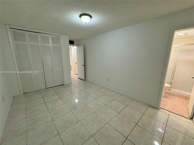 unfurnished bedroom featuring a closet, a textured ceiling, and ensuite bathroom