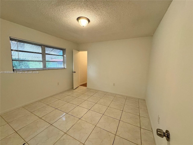 spare room with light tile patterned floors and a textured ceiling